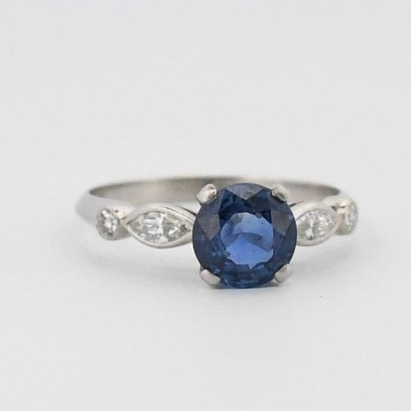 Art Deco Platinum Rich Blue Round Brilliant Cut Natural Sapphire Solitaire Engagement Ring  slightly angled to the left highlighting the marquise shanks 